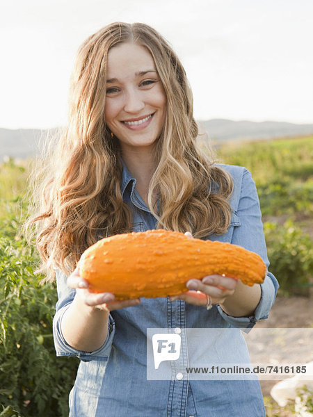 Portrait of young woman holding squash
