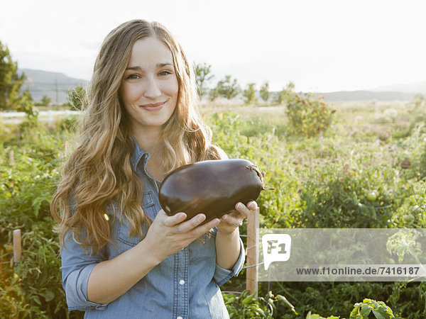 Portrait of young woman holding eggplant