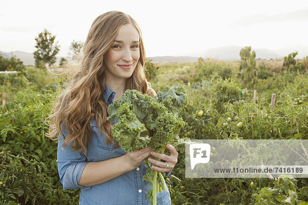 Portrait of young woman holding kale
