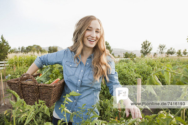Portrait of young woman harvesting vegetables