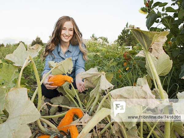 Portrait of young woman harvesting squash
