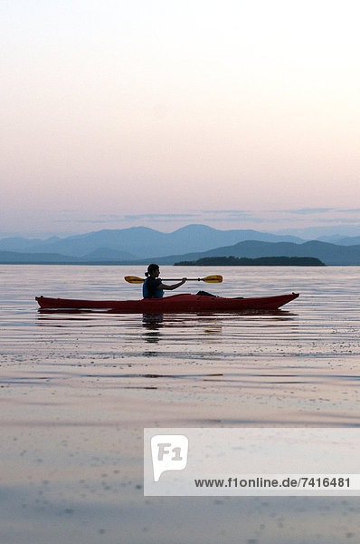 Woman kayaking on Lake Champlain at sunset in Burlington  Vermont.