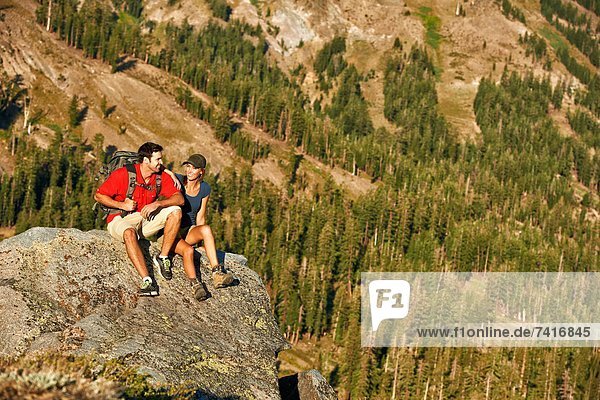 A couple takes a break on a rock as they soak in the beauty of a Summer hiking adventure.