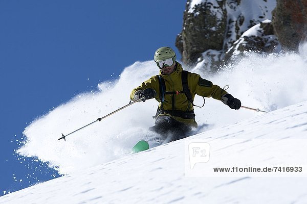 One skier making a hard turn in fresh powder.