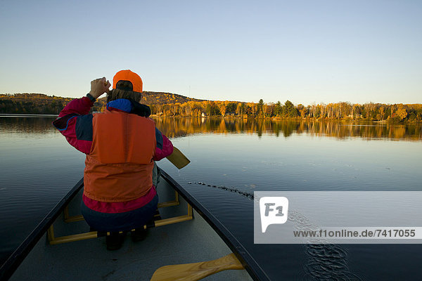 A boy in a life jacket paddles a canoe on a lake near Barry's Bay  Ontario  Canada.