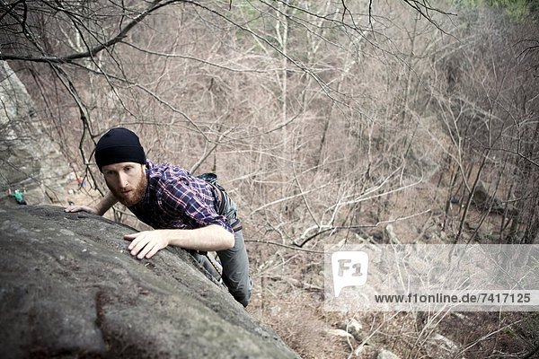 A male rock climber tops on while climbing on a cold day in the northeast.