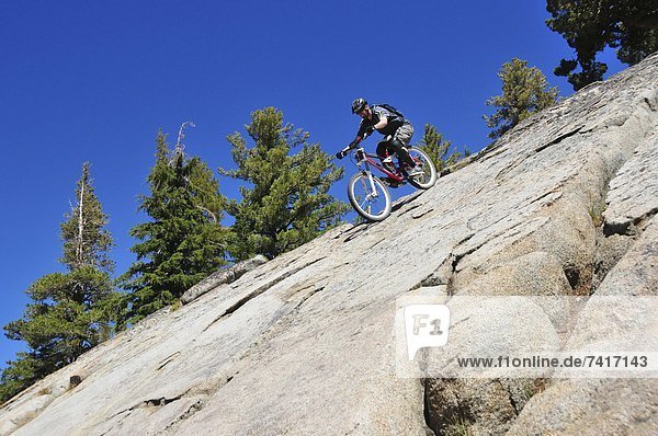 A mountain biker rides down an extremely steep slab of granite at Kirkwood Mountain Resort  CA.