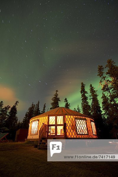 The Aurora Borealis (Northern Lights) over an illuminated yurt outside of Whitehorse in the Yukon Territory  Canada.
