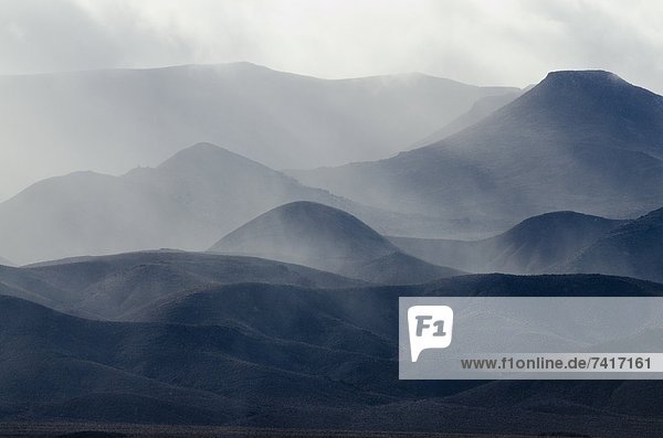 A storm engulfs the mountains in the Nevada desert along Highway 95.