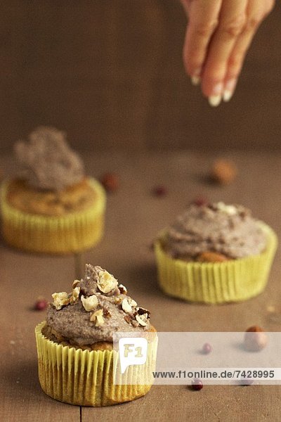 Cupcakes mit süsser Bohnencreme und karamellisierten Nüssen werden dekoriert