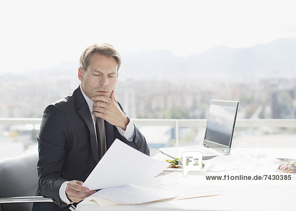 Businessman with lunch reviewing paperwork