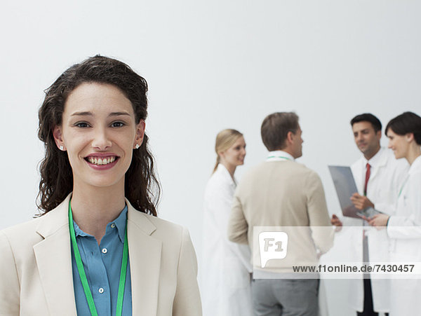 Portrait of smiling businesswoman with doctors in background