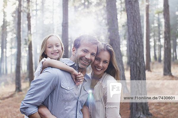 Porträt einer lächelnden Familie in sonnigen Wäldern