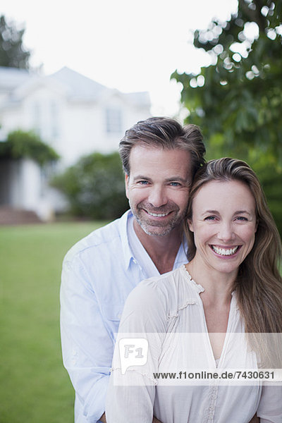 Portrait des lächelnden Paares im Hof mit Haus im Hintergrund