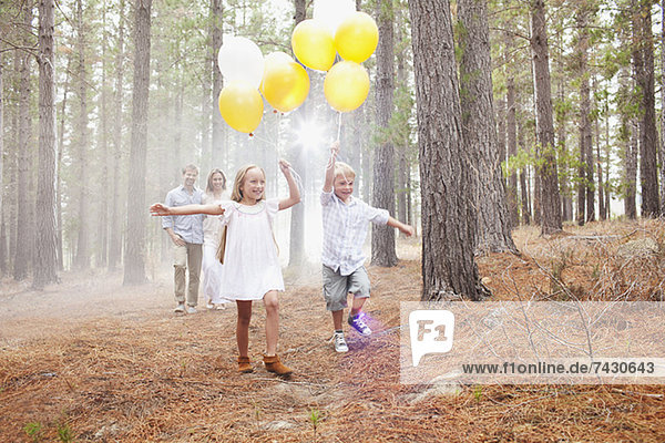 Glückliche Familie mit Ballons im Wald