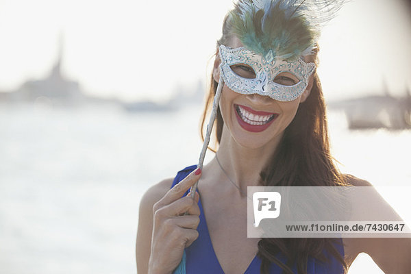 Porträt einer lächelnden Frau mit Maske am Wasser in Venedig