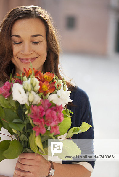 Lächelnde Frau riecht Blumenstrauß