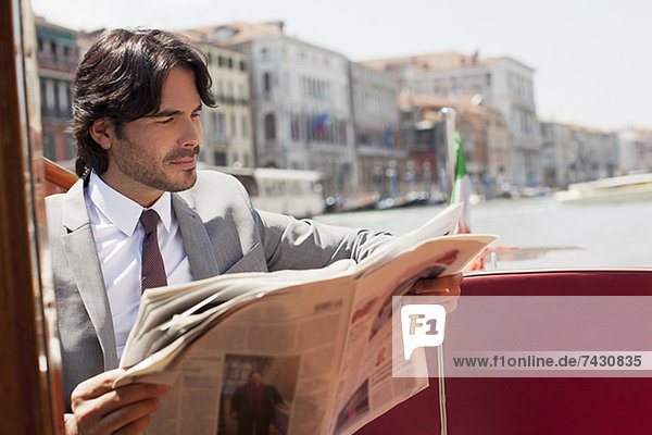 Geschäftsmann liest Zeitung auf dem Schiff in Venedig