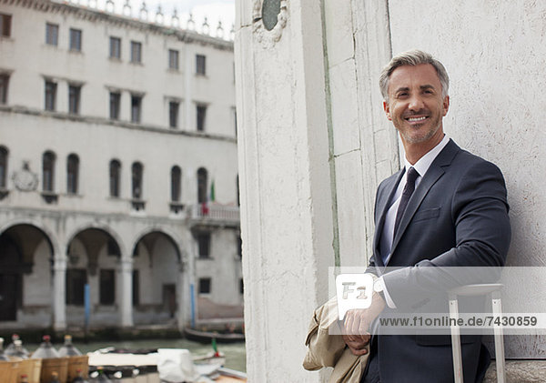 Porträt eines lächelnden Geschäftsmannes mit Koffer in Venedig