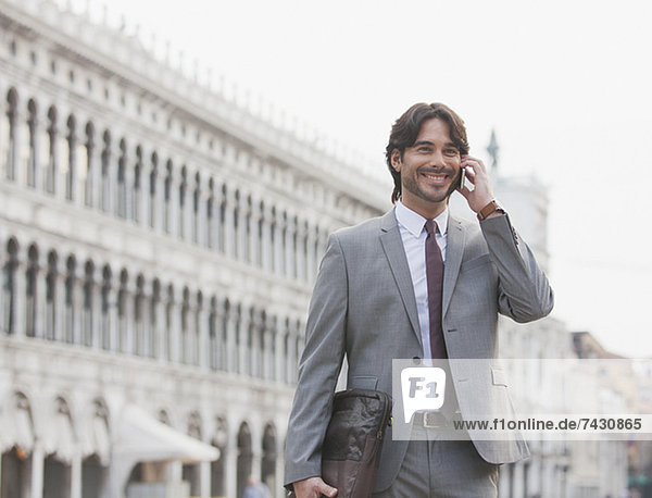Lächelnder Geschäftsmann beim Telefonieren auf dem Markusplatz in Venedig