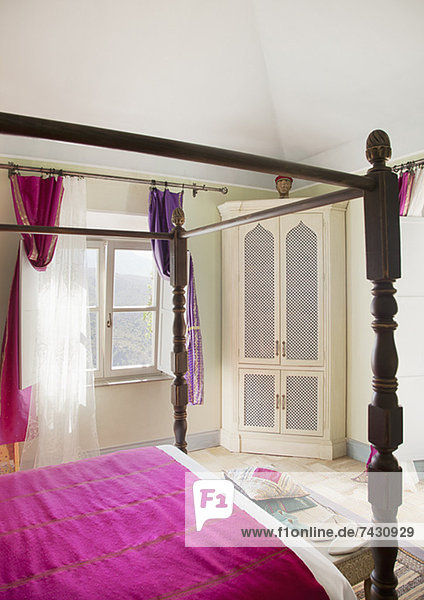 Himmelbett mit violetter Bettwäsche im Schlafzimmer