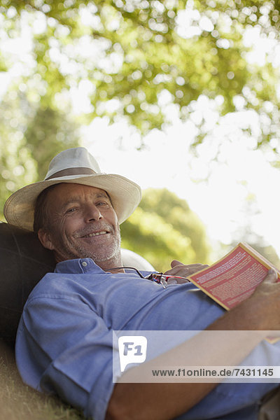 Porträt eines lächelnden Mannes im Gras mit Buch