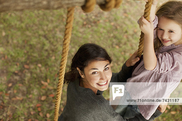 Portrait of smiling mother and daughter on swing
