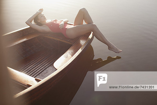 Gelassene Frau beim Sonnenbaden im Boot auf dem See