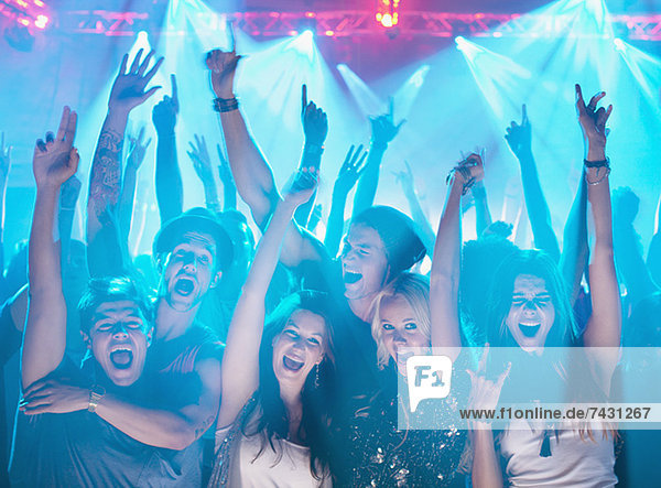 Portrait of enthusiastic crowd with arms raised at concert