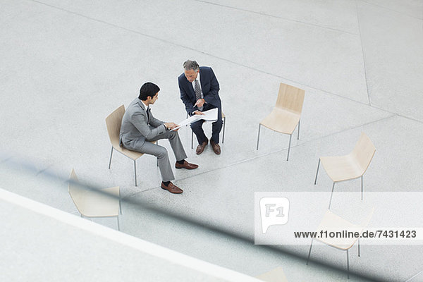 Geschäftsleute  die den Papierkram im Kreis der Stühle besprechen