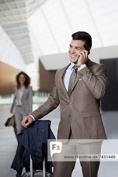 Lächelnder Geschäftsmann beim Telefonieren am Flughafen