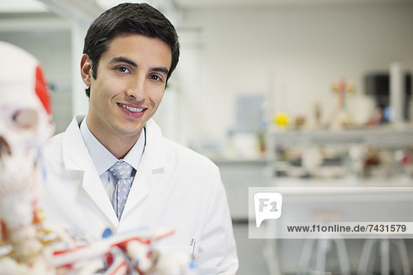Porträt eines lächelnden Wissenschaftlers mit anatomischem Modell im Labor