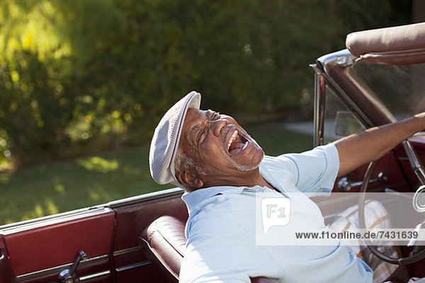 Lachender älterer Mann beim Cabriofahren