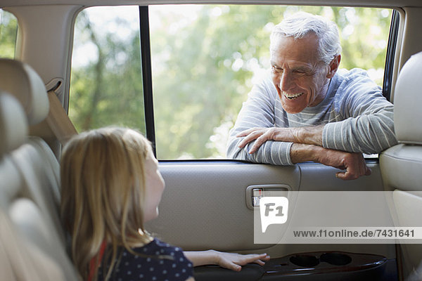 Older man talking to granddaughter in car window