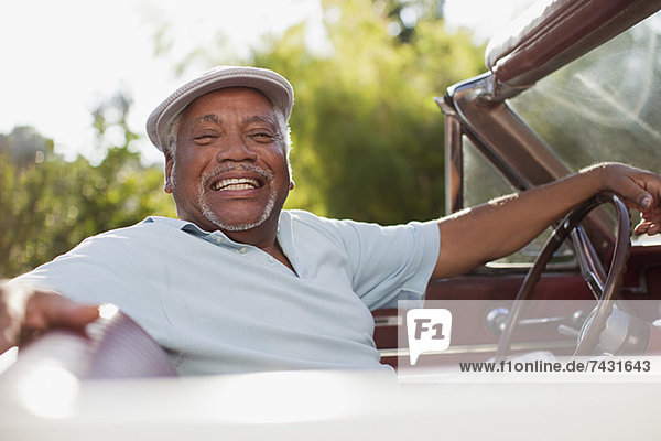 Smiling older man driving convertible