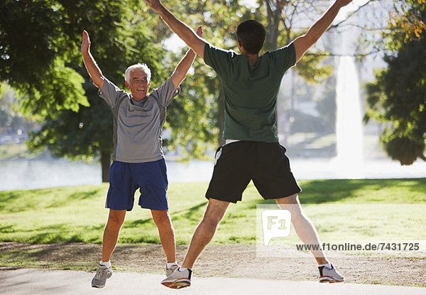 Older men doing jumping jacks outdoors
