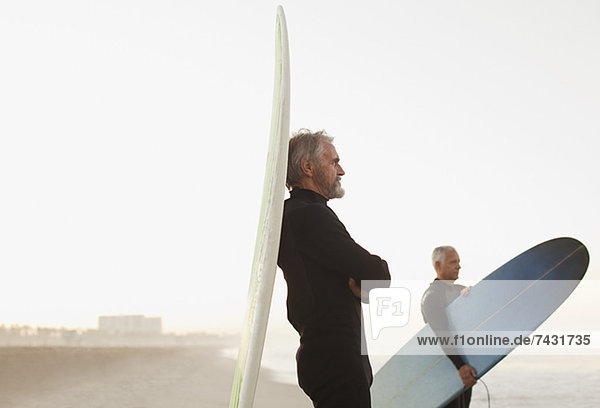 Ältere Surfer  die sich am Strand an Bord lehnen