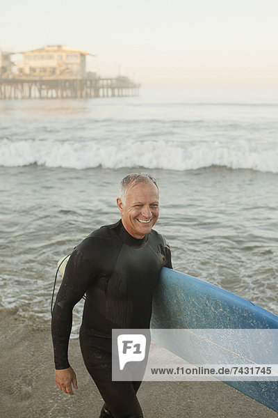 Ältere Surfer mit Brett am Strand