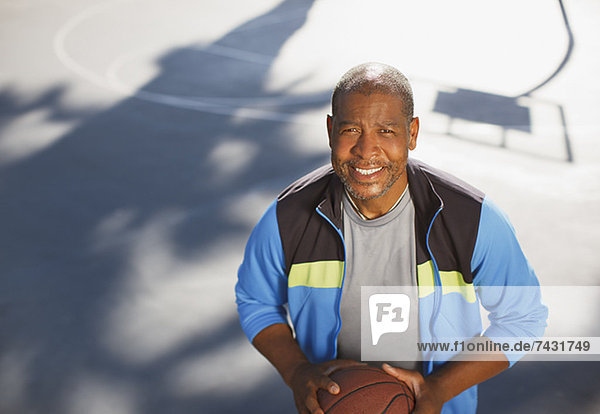 Älterer Mann spielt Basketball auf dem Platz