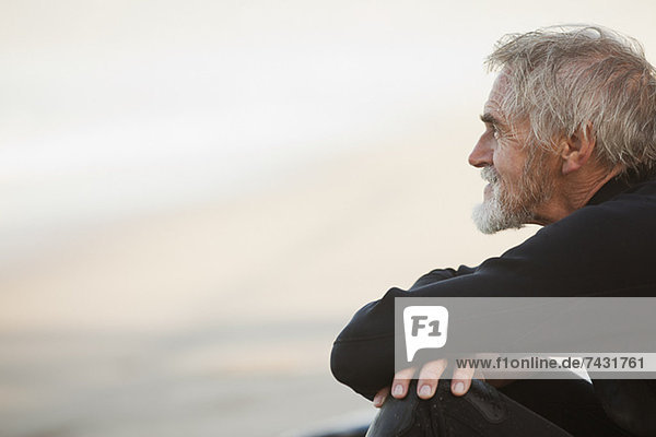 Älterer Surfer am Strand sitzend