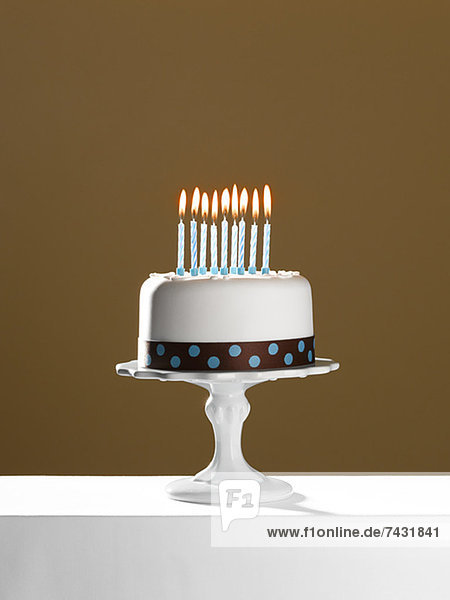 Geburtstagskuchen mit angezündeten Kerzen auf dem Kuchenständer