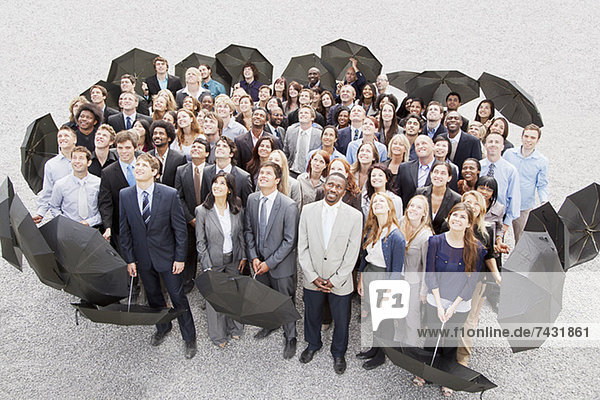 Porträt von lächelnden Geschäftsleuten mit Regenschirmen  die nach oben schauen