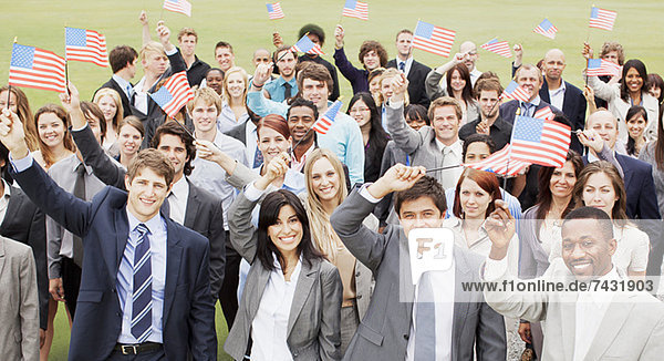 Portrait of smiling business people waving American flags overhead