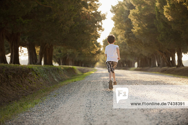 Caucasian boy running on dirt road