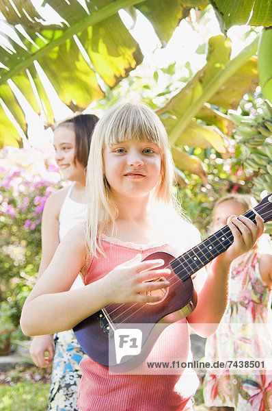 Caucasian girl playing ukulele outdoors