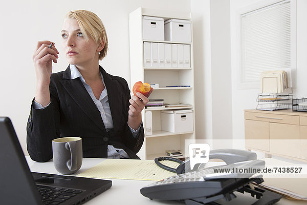 Europäer  Geschäftsfrau  Schreibtisch  Büro  essen  essend  isst