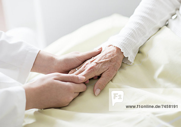 Pflegerin hält die Hand einer Seniorin