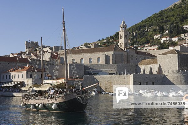 Tourist boat in the old harbour with the bell tower of the Franciscan Monastery in the background  Old Town  Dubrovnik  UNESCO World Heritage Site  Croatia  Europe