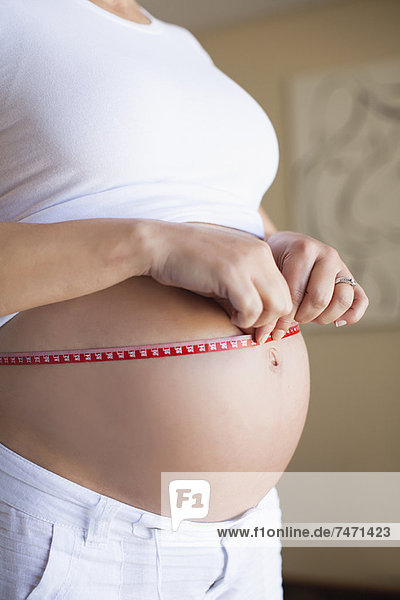 Schwangere Frau  die den Bauch misst