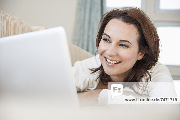 Smiling woman using laptop on sofa